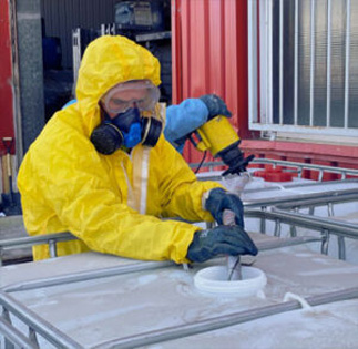 Preparación y acondicionamiento de disolventes y residuos químicos | ECOVALL Operario con equipo de protección realizando el acondicionamiento de disolventes y productos químicos industriales en un contenedor.